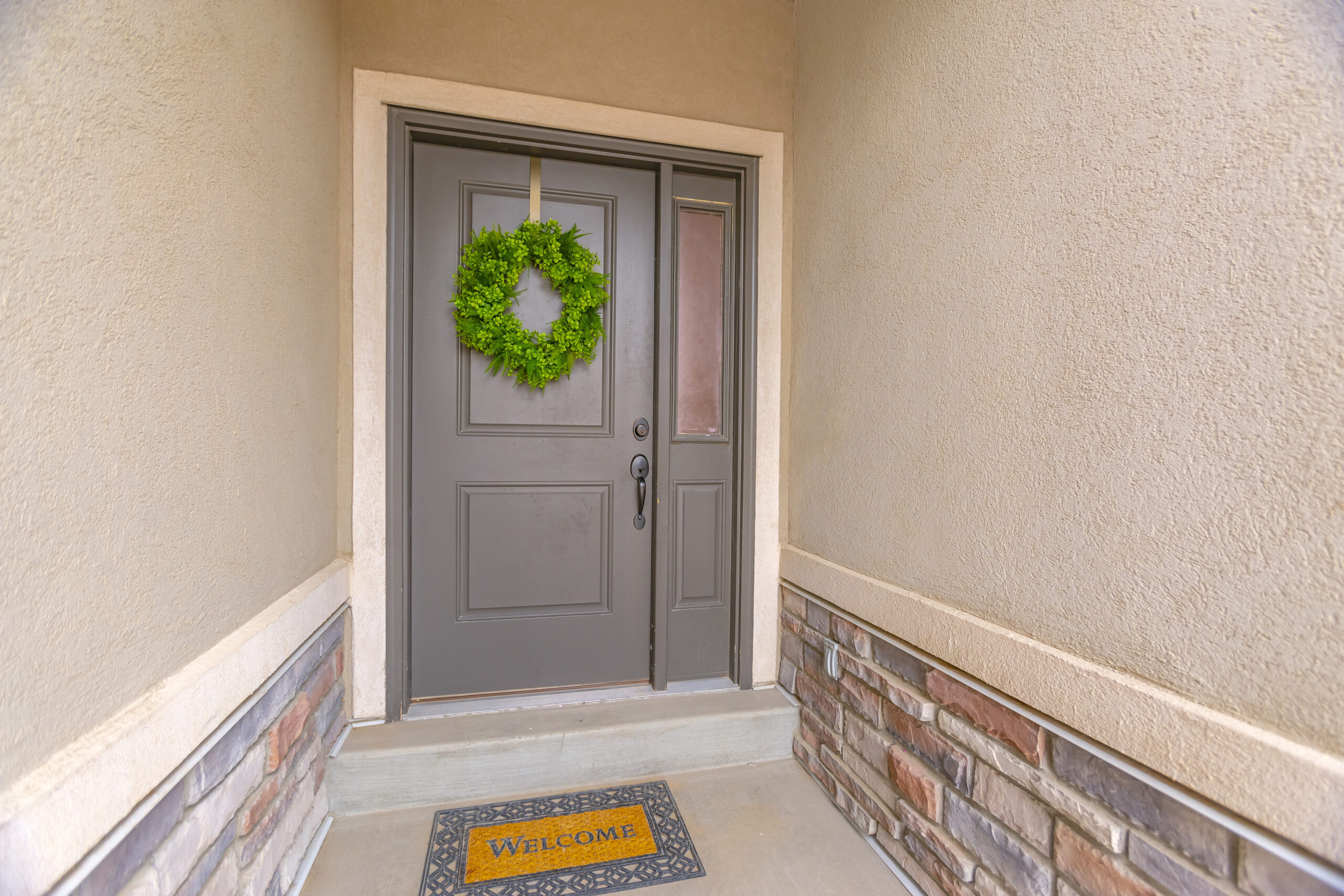Doors gray front door of a home with a simple green wreath and sidelight